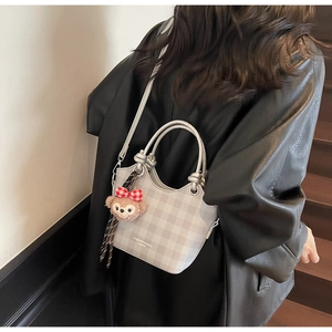 Detail shot of the gray plaid bucket bag showing wave-cut edges and metal handle ring