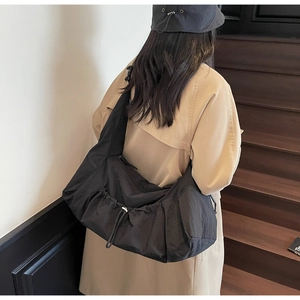 Detail view of large black nylon tote bag with drawstring closure and side zipper pocket