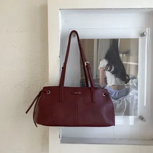 Dettaglio della borsa in ecopelle rosso scuro con logo metallico e coulisse decorative