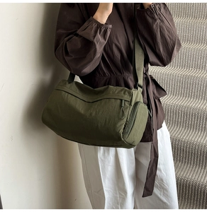 Detail view of large dark green cylindrical tote bag with side zipper and canvas texture