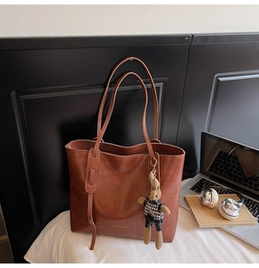 Dettaglio della borsa tote marrone vintage con texture in pelle e ciondolo a coniglio