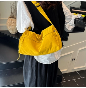 Fashionable bright yellow nylon tote bag shown on model in a stylish indoor setting