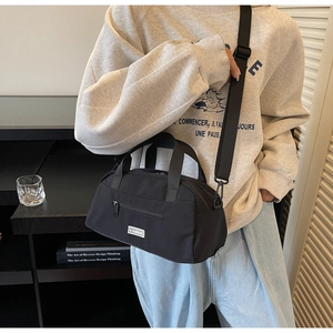 Minimalist black nylon pillow bag with adjustable wide shoulder strap and brand label