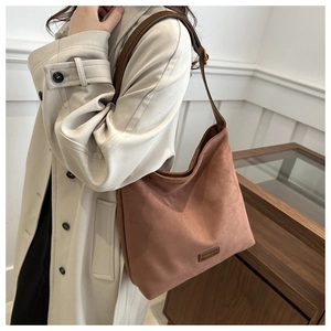 Detailed back view of a vintage caramel suede bucket bag worn with a beige trench coat