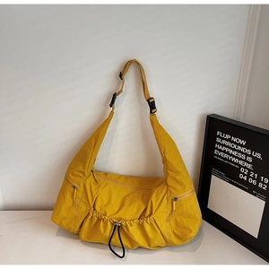 Detail view of yellow nylon tote bag showing zipper pockets and adjustable buckle strap