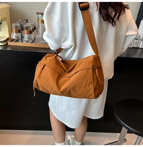 Detail of a brown nylon tote bag featuring a wide shoulder strap and long zipper pullers