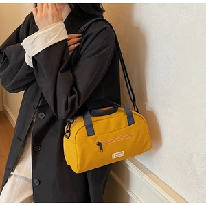 Detail view of yellow canvas pillow bag featuring a front zipper pocket and JL FASHION label