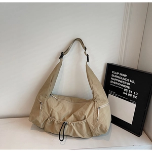 Close-up detail of khaki nylon tote bag showing multiple zipper pockets and drawstring design