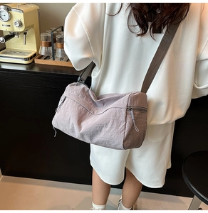 Detail view of light purple nylon tote bag with adjustable shoulder strap in coffee shop setting