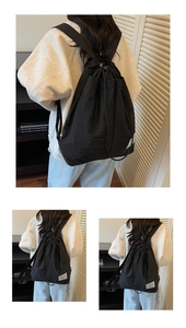 Macro shot of minimalist black drawstring backpack featuring a side woven label detail