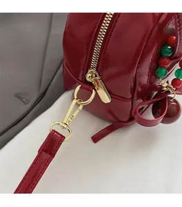Détail d'un sac oreiller en cuir verni rouge avec fermeture éclair et ferrures dorées de qualité