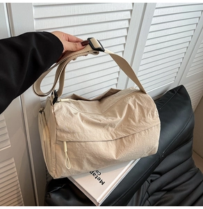 Detail of beige nylon cylindrical tote bag with wide shoulder strap and metal buckle