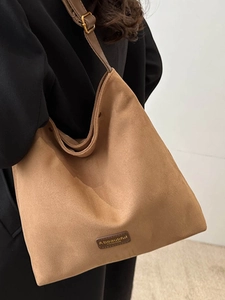 Brown faux suede oversized tote bag with adjustable straps on black blazer model
