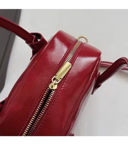 Détail d'un sac à main rouge brillant avec fermeture éclair dorée et coutures précises