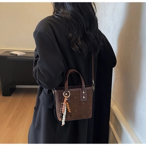 Deep brown suede tote bag with star patterns and beaded tassel on a female model