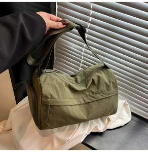 Close-up of military green nylon duffel bag with wide shoulder strap and side zipper