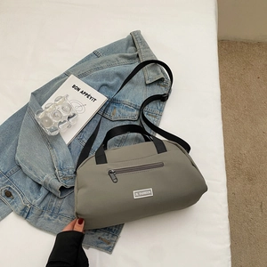 Detail of grey-green nylon pillow bag with JL FASHION metal logo and black strap