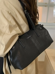 Borsa tote minimalista in pelle nera con texture naturale e sottile tracolla regolabile