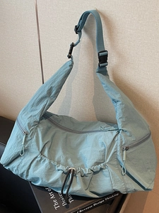 Minimalist light blue nylon tote bag with drawstring pocket and adjustable strap