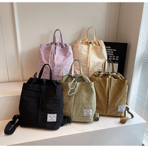 Detailed view of five multi-color drawstring backpacks in nylon fabric with brand label