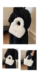 Detail of white plush handbag featuring a red embroidered label and silver chain strap
