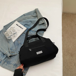 Detail of black nylon pillow bag with JL FASHION metal logo and adjustable shoulder strap