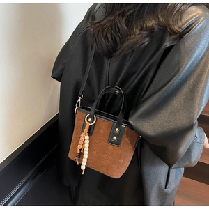 Detail of brown suede bucket bag with star embossing, beaded charms and fringe tassels