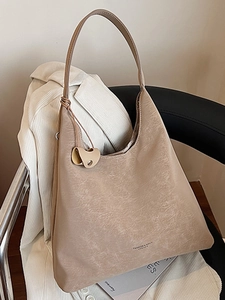 Sac fourre-tout chic en similicuir beige texturé accroché à une chaise avec magazine