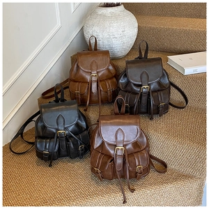 Detailed arrangement of four retro leather backpacks in various colors on rustic stairs