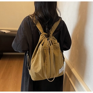 Rear view of a khaki drawstring backpack with a minimalist Japanese design on a model