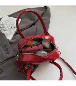 Détail du sac polochon en cuir verni rouge montrant l'intérieur spacieux et la fermeture éclair