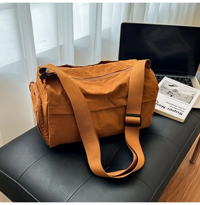Detail view of water-resistant orange nylon fabric and zip pocket on a cylinder bag