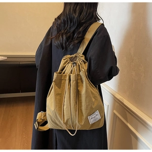 Detail of khaki drawstring backpack featuring water-resistant fabric and minimalist brand label