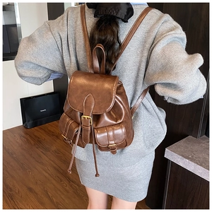 Close-up of vintage brown leather backpack with front buckle pockets and flap closure