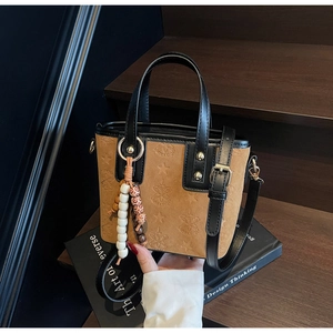 Detail view of brown suede handbag with embossed star patterns and beaded charm strap