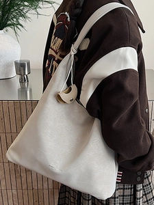 Sac fourre-tout beige crème tendance pour femme avec pendentif dans un décor intérieur