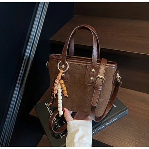 Close-up of brown textured bag with embossed star patterns and beaded tassel charm