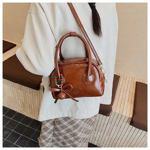 Gros plan d'un sac oreiller en cuir brillant marron avec pendentif nœud perlé