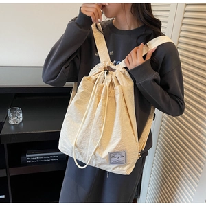 Detailed view of cream drawstring backpack with crinkled fabric and vintage brand label