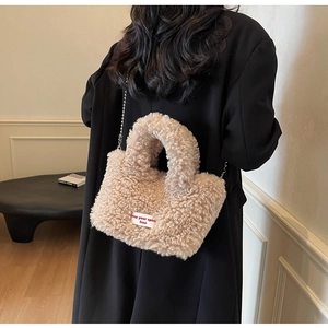 Detail of beige faux shearling handbag with metal chain strap and woven label