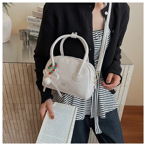 Détail du sac Boston en cuir blanc avec logo doré et pendentif décoratif perlé