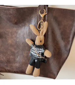 Detail of a chic rabbit bag charm with khaki knit texture and golden chain on a tote