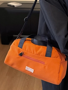 Chic orange pillow crossbody bag for women with black nylon straps and zipper detail