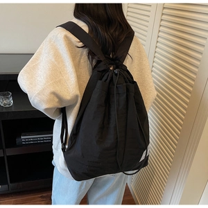 Close-up of wide straps on black drawstring backpack with waterproof nylon fabric texture