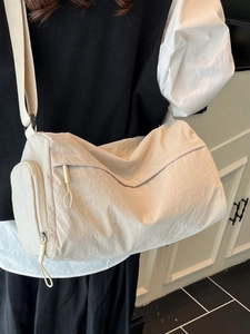 Minimalist beige nylon tote bag with cylindrical design and wide shoulder strap