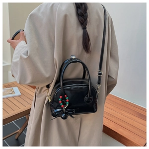Détail d'un sac oreiller noir brillant avec un nœud en soie et un charme en perles