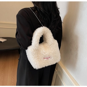 Detail of white faux fur tote bag featuring a red letter label and silver bead chain strap