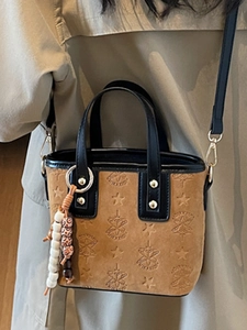 Brown suede bucket bag with star embossing and black leather straps on a model