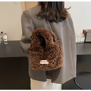 Close-up of fluffy brown plush tote bag with embroidered label and silver metal chain strap