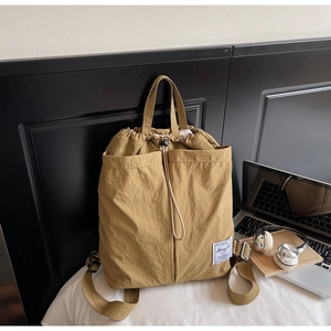 Detail of khaki drawstring backpack featuring natural nylon texture and side pockets